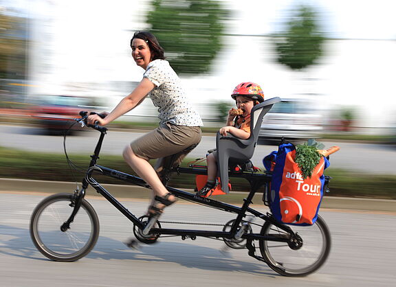 Frau mit Kind und Einkauf auf Lastenrad