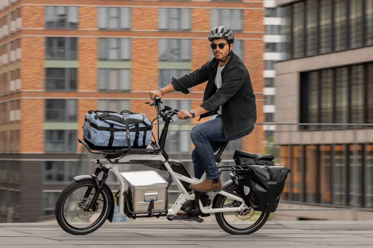 Eine beladenes CaGo Lastenrad auf der Straße, gefahren von einem Mann. 