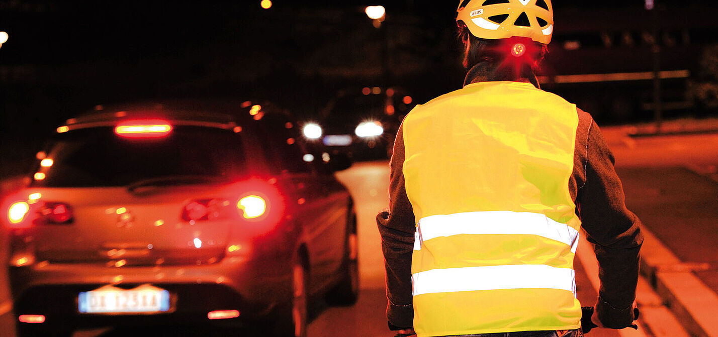 Mit Reflexweste und Helm in Signalfarbe samt integriertem Rücklicht ist dieser Radfahrer rundum bestens sichtbar.