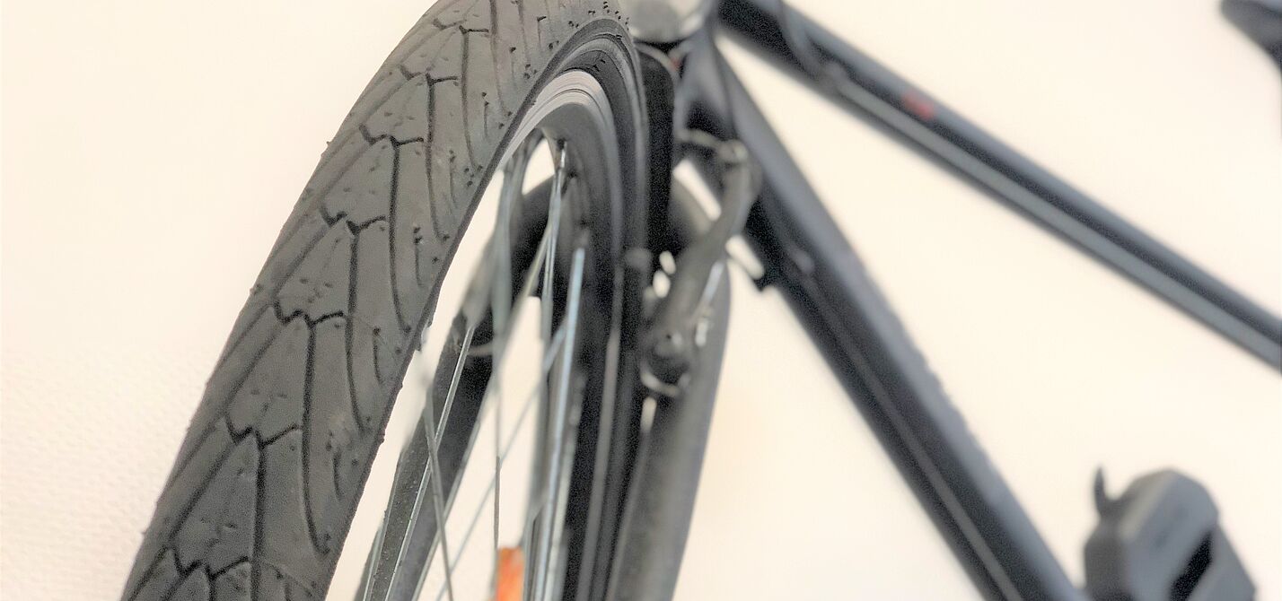 Aufnahme eines Reifens frontal, Fahrrad verschwommen im Hintergrund. 